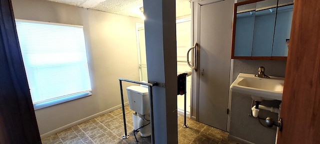 laundry room with a textured ceiling and baseboards