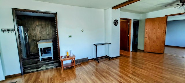 living room with wood finished floors, a ceiling fan, a fireplace, visible vents, and baseboards
