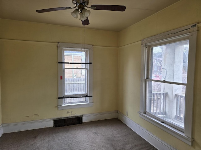 carpeted spare room with a ceiling fan, baseboards, and a healthy amount of sunlight