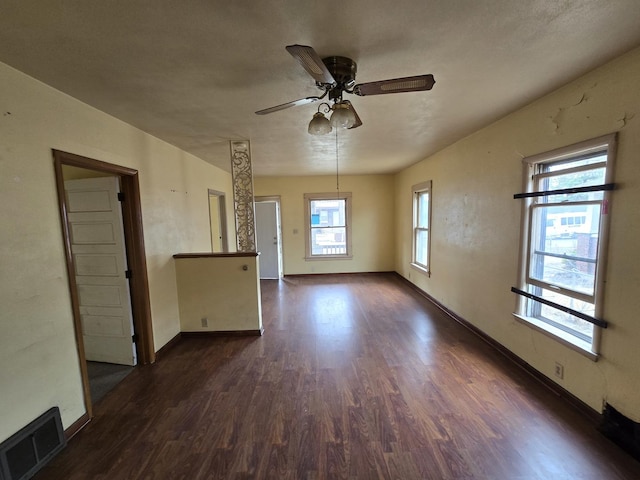 spare room featuring baseboards, a ceiling fan, dark wood-style flooring, and visible vents