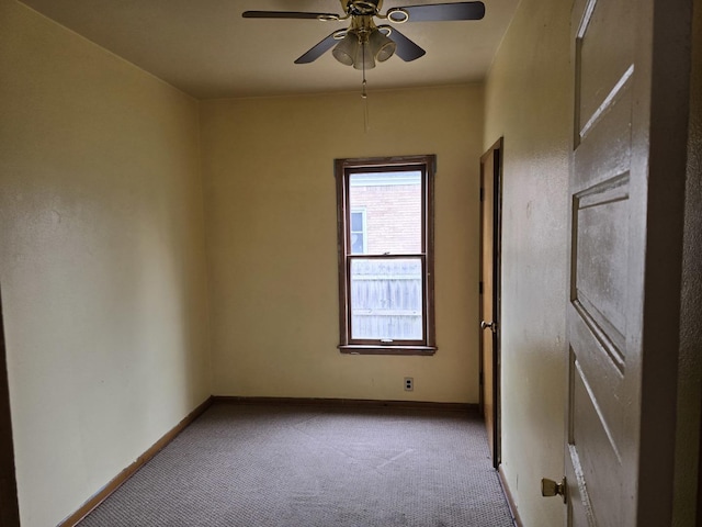 carpeted empty room featuring baseboards and ceiling fan