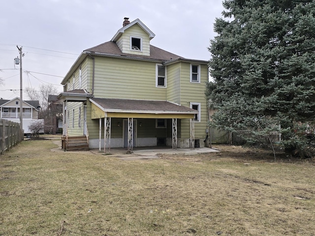 rear view of house featuring fence, roof with shingles, a chimney, a patio area, and a lawn