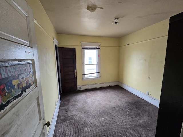 spare room with carpet floors, baseboards, and a baseboard heating unit