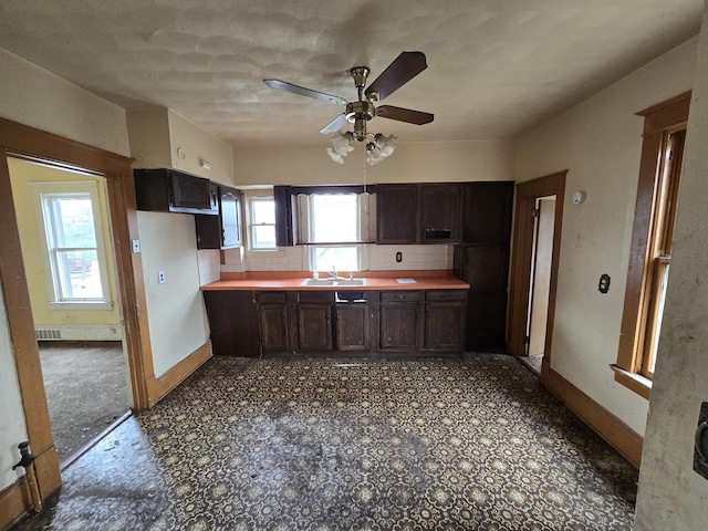 kitchen with baseboards, a ceiling fan, dark brown cabinetry, and a sink