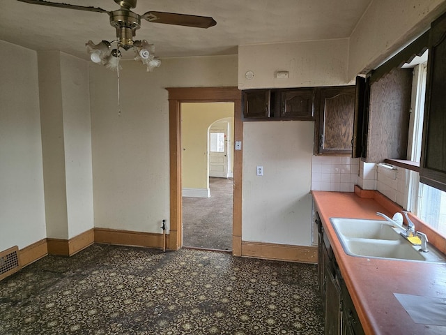 kitchen featuring a sink, arched walkways, ceiling fan, and a wealth of natural light