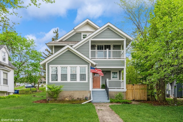 view of front of home with a balcony, a front lawn, and fence