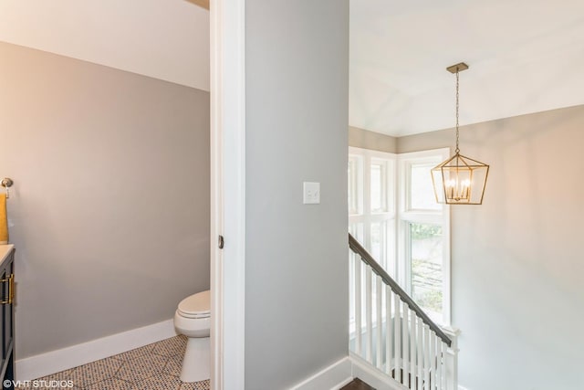 interior space with toilet, a notable chandelier, and baseboards