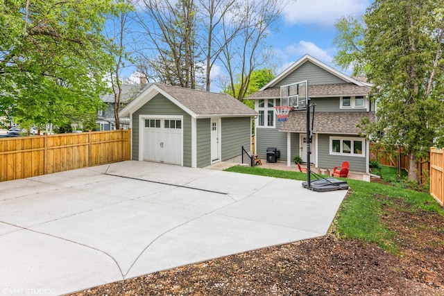 view of front of property with an outbuilding, roof with shingles, a garage, and a fenced backyard