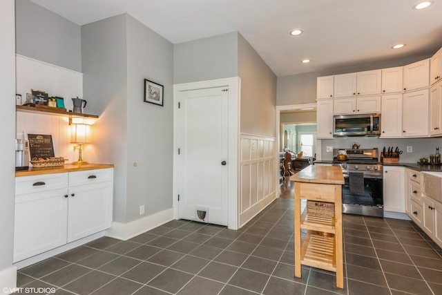 kitchen with stainless steel appliances, dark tile patterned flooring, recessed lighting, and white cabinets