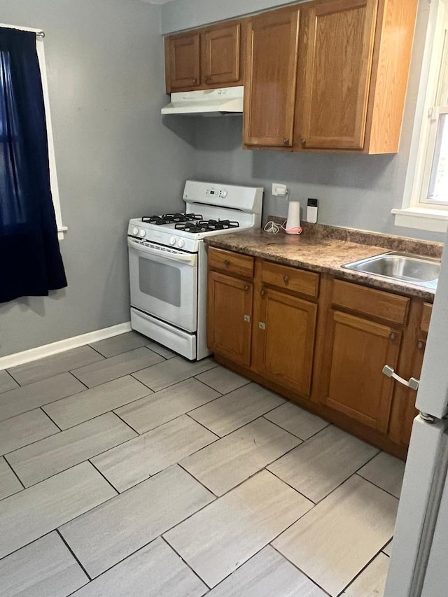 14534 S Grant St, Dolton, IL 60419 - kitchen featuring gas range gas stove, under cabinet range hood, brown cabinetry, and wood finish floors