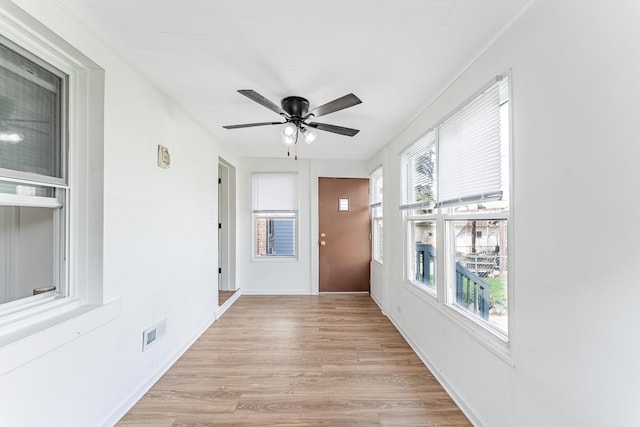 doorway with ceiling fan, visible vents, light wood finished floors, and a healthy amount of sunlight