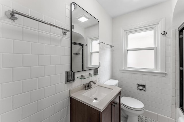 bathroom with vanity, tile walls, and toilet