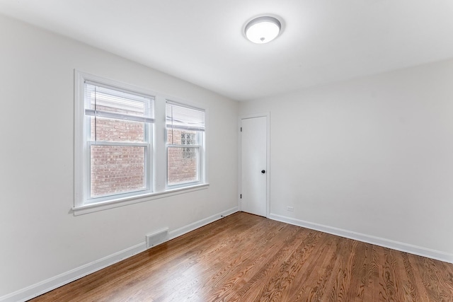 unfurnished room with baseboards, visible vents, and wood finished floors