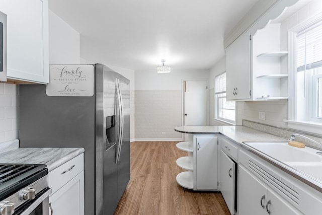 kitchen featuring light wood finished floors, open shelves, light countertops, and white cabinets