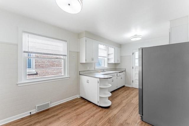 kitchen with freestanding refrigerator, visible vents, open shelves, and a sink