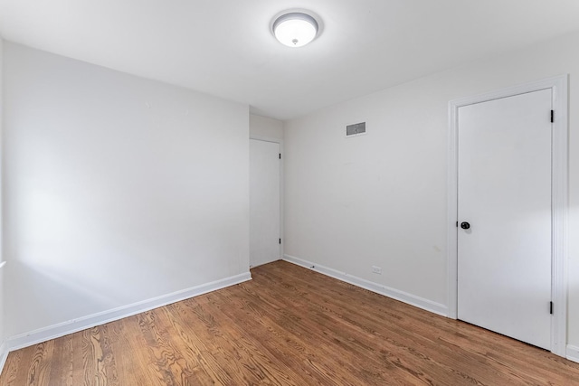 unfurnished room with visible vents, wood finished floors, and baseboards
