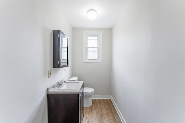 bathroom featuring vanity, toilet, wood finished floors, and baseboards