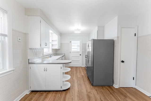 kitchen featuring freestanding refrigerator, light wood-style flooring, open shelves, and white cabinets