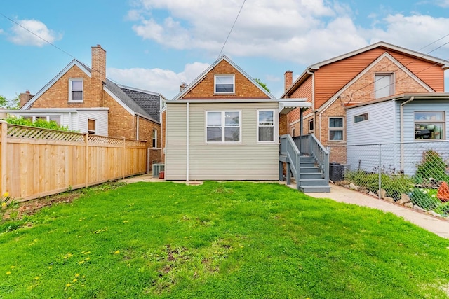 back of property featuring a yard, a fenced backyard, and central AC