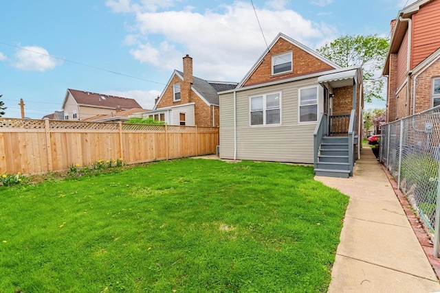 rear view of property featuring a yard and a fenced backyard