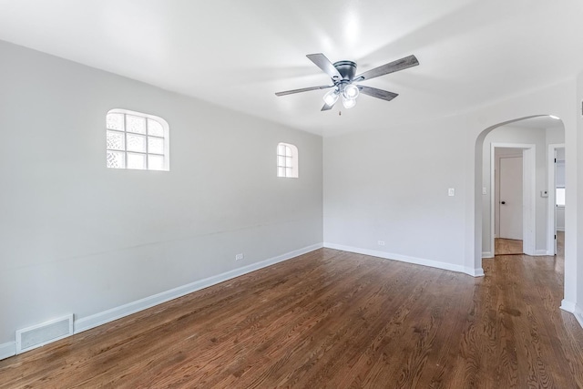 empty room featuring arched walkways, ceiling fan, visible vents, and plenty of natural light