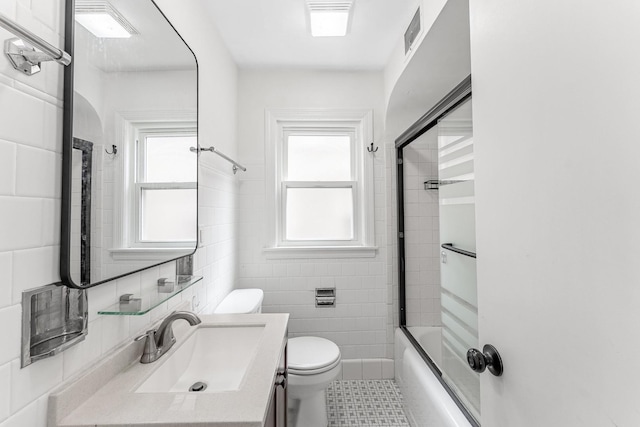 full bath with toilet, tile walls, plenty of natural light, visible vents, and vanity