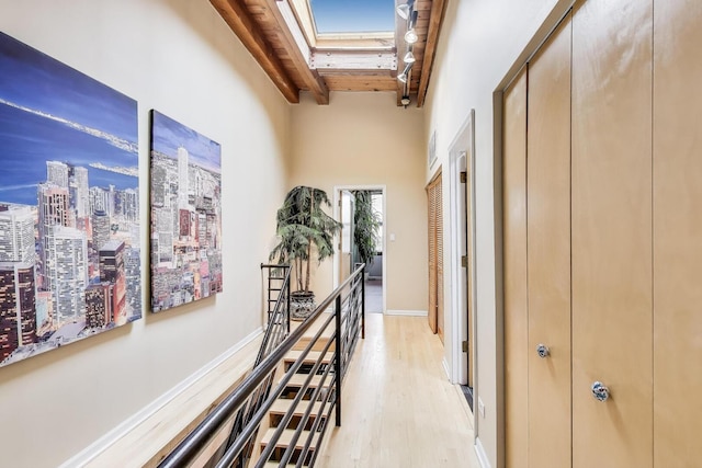 hall featuring a skylight, beamed ceiling, light wood-type flooring, wood ceiling, and a city view