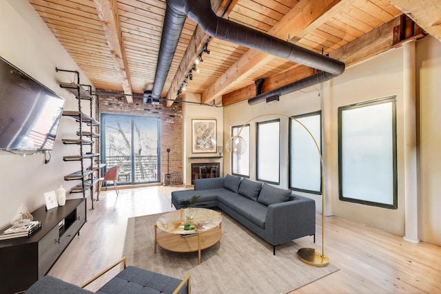 living room featuring wood ceiling, wood finished floors, beam ceiling, and a glass covered fireplace