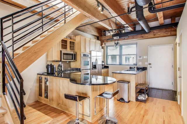 kitchen featuring a peninsula, appliances with stainless steel finishes, wooden ceiling, beamed ceiling, and light wood-style flooring