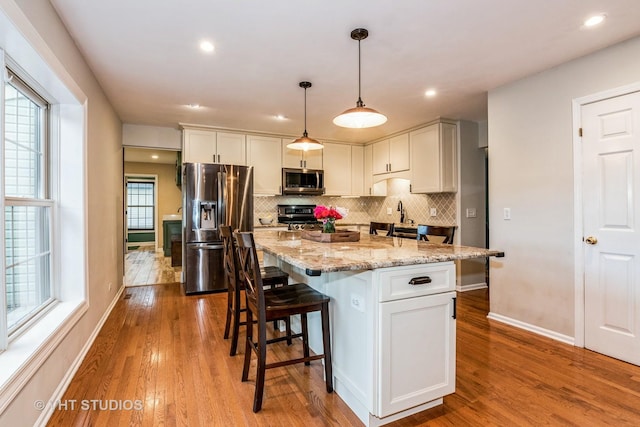 1057 Ponca Dr, Batavia, IL 60510 - kitchen with stainless steel appliances, wood finished floors, a breakfast bar, tasteful backsplash, and recessed lighting