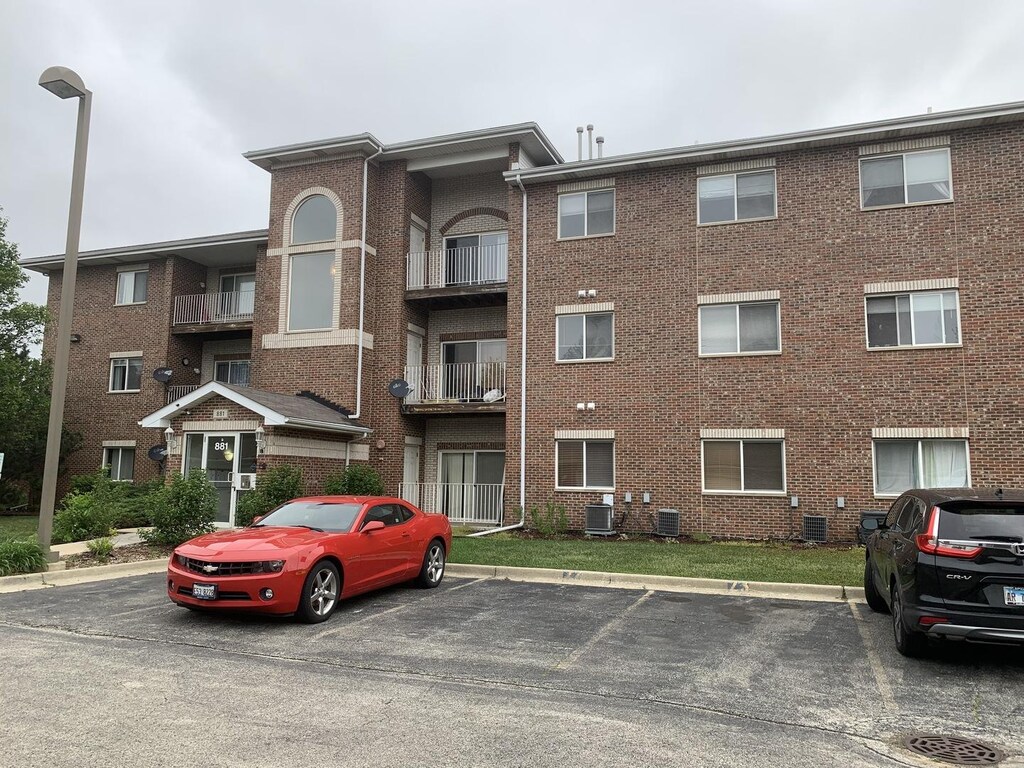 view of building exterior with central AC and uncovered parking