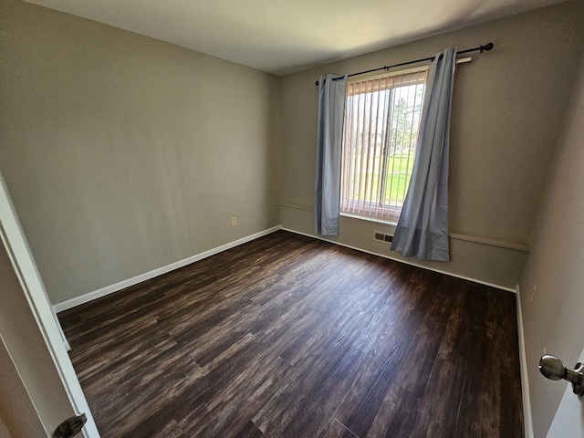 spare room featuring baseboards, dark wood finished floors, and visible vents
