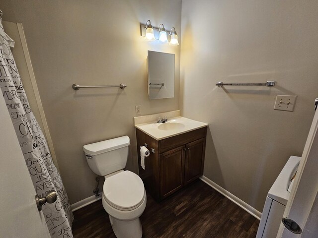 bathroom featuring toilet, baseboards, wood finished floors, and vanity
