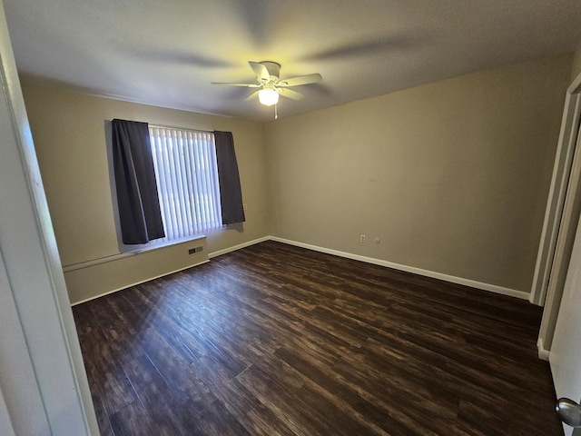 spare room featuring baseboards, ceiling fan, baseboard heating, and dark wood-type flooring