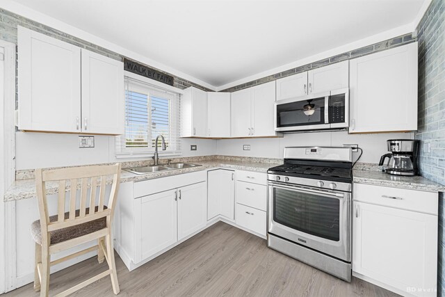 16165 Haven Ave, Orland Hills, IL 60487 - kitchen with appliances with stainless steel finishes, a sink, light countertops, light wood-style flooring, and white cabinetry
