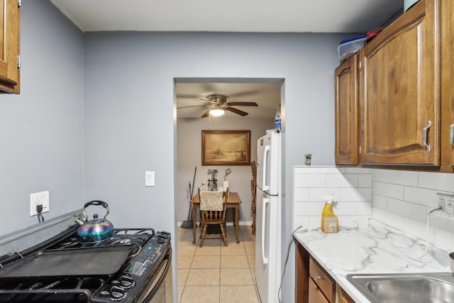 600 Mesa Dr Unit 103, Hoffman Estates, IL 60169 - kitchen featuring gas range, light tile patterned flooring, brown cabinets, ceiling fan, and backsplash