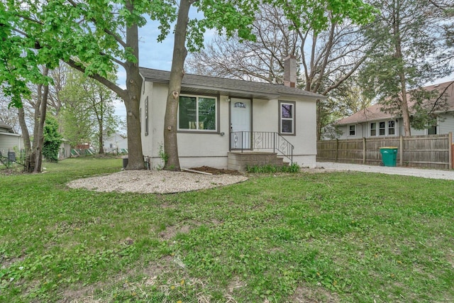 413 Wheeler Ave, Joliet, IL 60436 - view of front facade with a chimney, fence, stucco siding, and a front yard