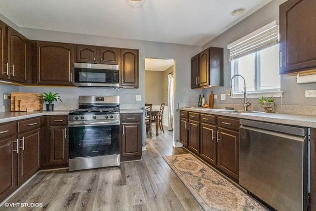 4524 Deames St, Plano, IL 60545 - kitchen with dark brown cabinetry, light wood-style floors, light countertops, a sink, and appliances with stainless steel finishes