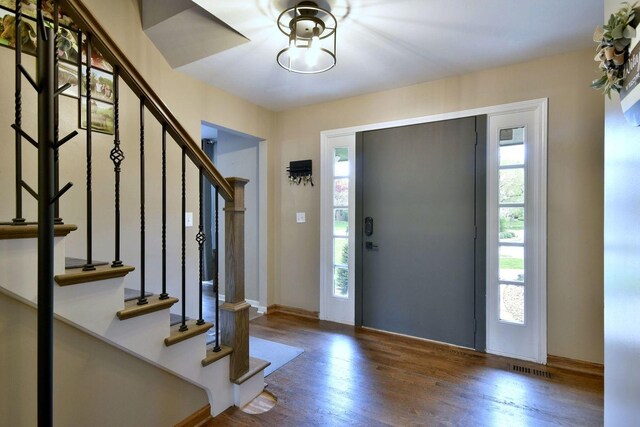 entryway with stairs, visible vents, and wood finished floors