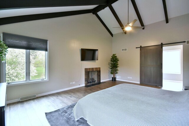 bedroom with visible vents, wood finished floors, a fireplace, beamed ceiling, and baseboards