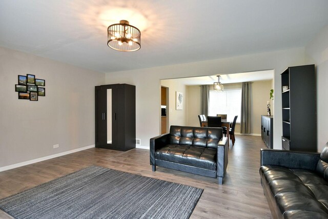 living area featuring baseboards, a notable chandelier, and wood finished floors