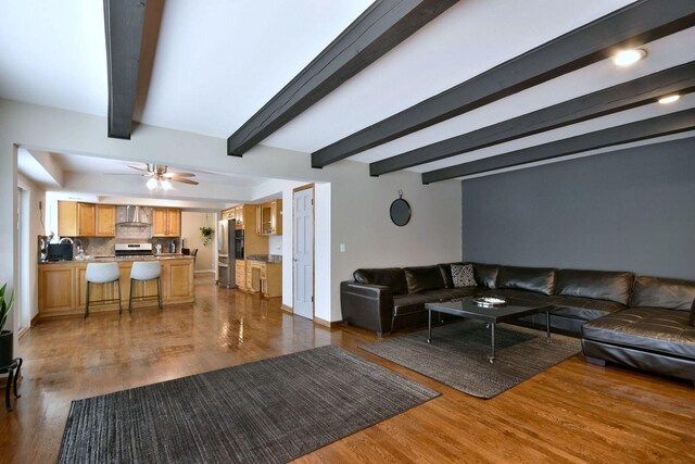living room featuring ceiling fan, wood finished floors, and beamed ceiling