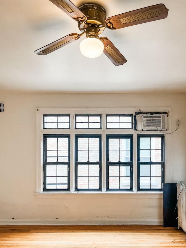 spare room with baseboards, a wall unit AC, light wood finished floors, and visible vents