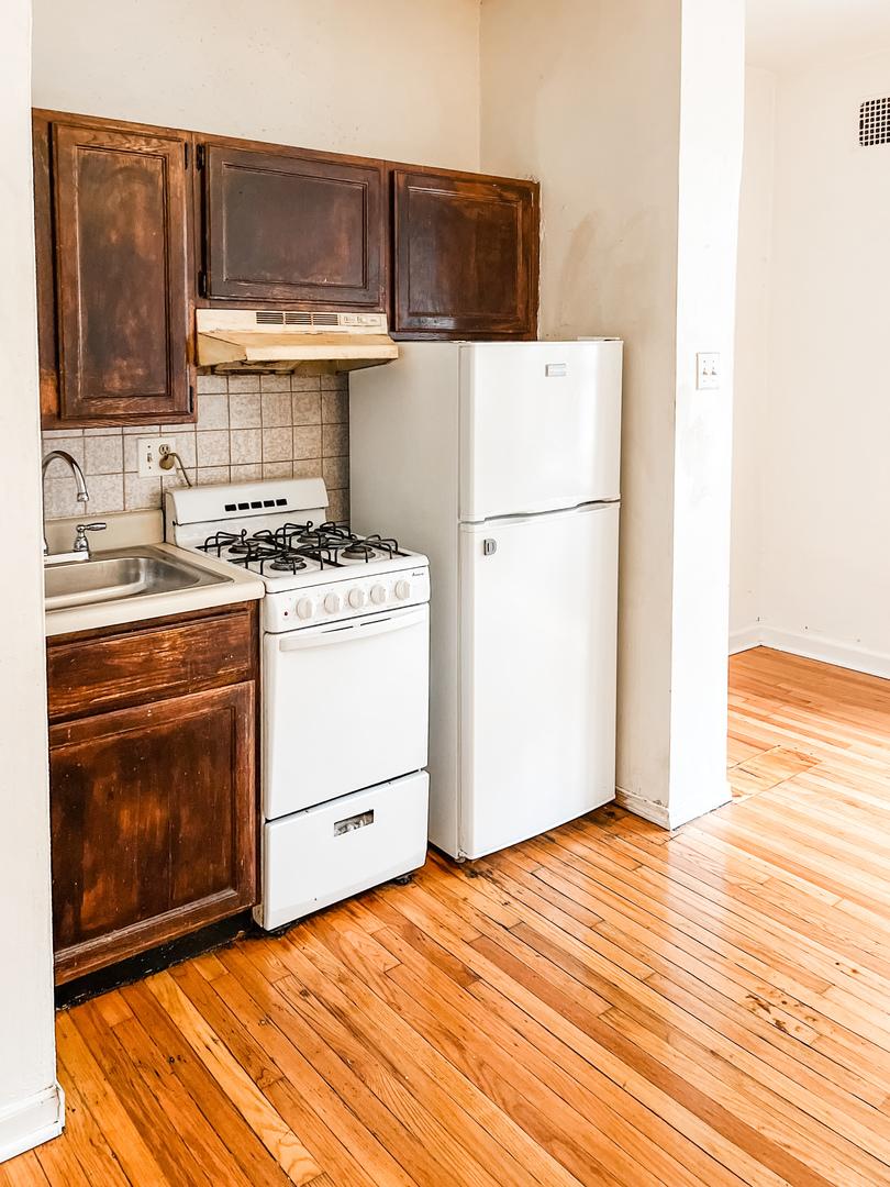 kitchen featuring dark brown cabinetry, a sink, white appliances, tasteful backsplash, and under cabinet range hood