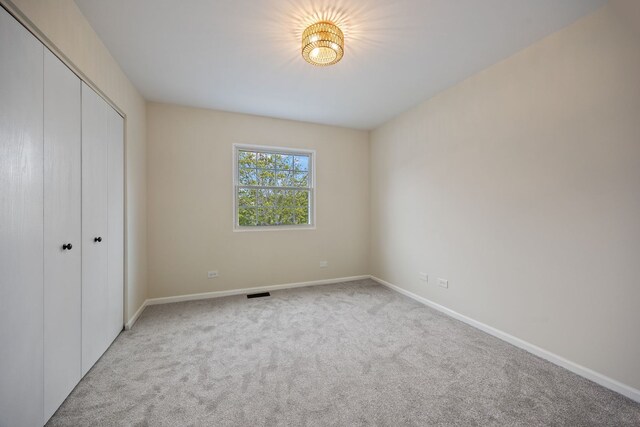 282 Ascot Ln, Streamwood, IL 60107 - unfurnished bedroom featuring light carpet, a closet, and baseboards