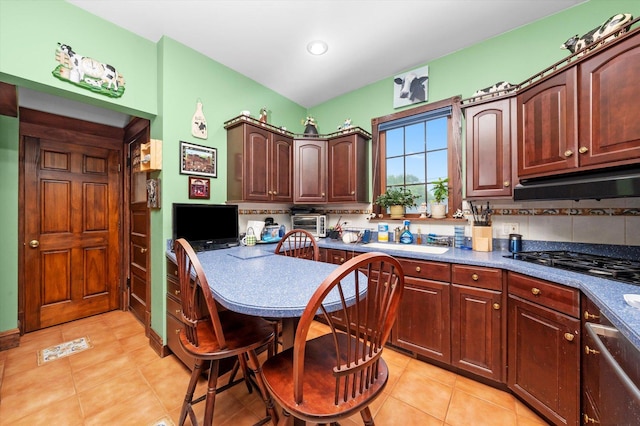 606 N Brainard Ave, La Grange Park, IL 60526 - kitchen with light tile patterned floors, black gas cooktop, under cabinet range hood, decorative backsplash, and dark countertops