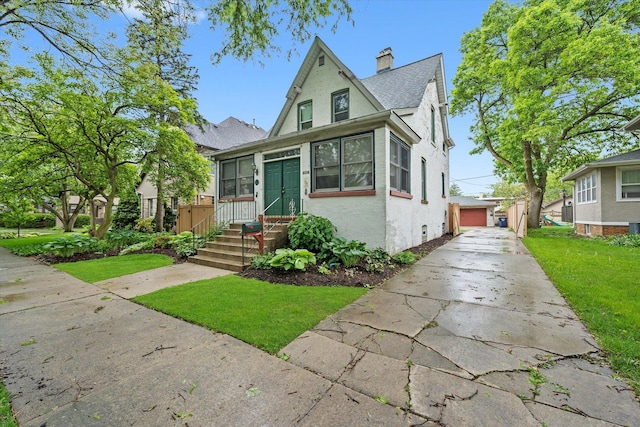 606 N Brainard Ave, La Grange Park, IL 60526 - view of front of home with an outdoor structure, a front yard, stucco siding, a detached garage, and a chimney