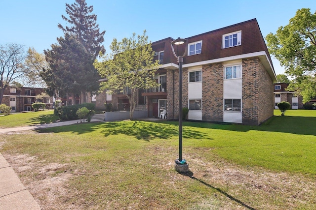 615 Hill Dr Unit 303, Hoffman Estates, IL 60169 - rear view of property with brick siding, a lawn, and mansard roof