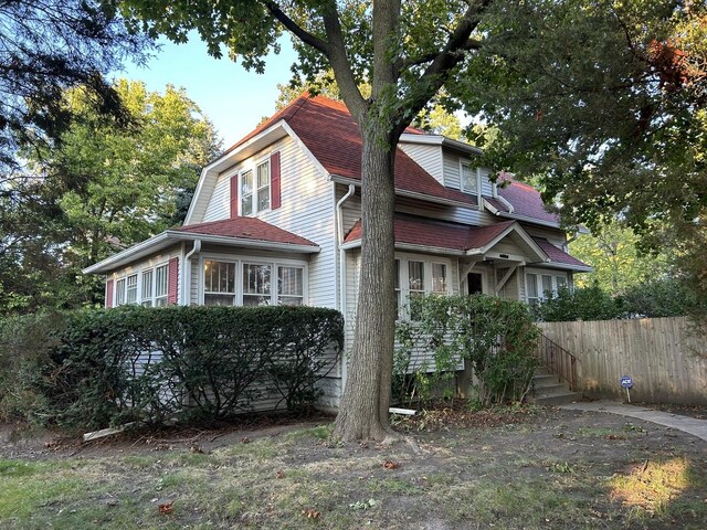 view of home's exterior featuring fence and roof with shingles