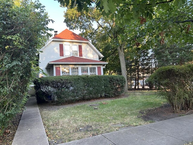 view of front facade with a chimney and a front lawn